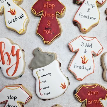 Decorative baby-themed cookies with playful fire-related phrases and designs.