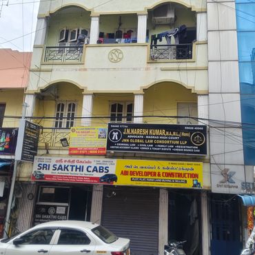 Three-story commercial building with various business signs and parked vehicles.