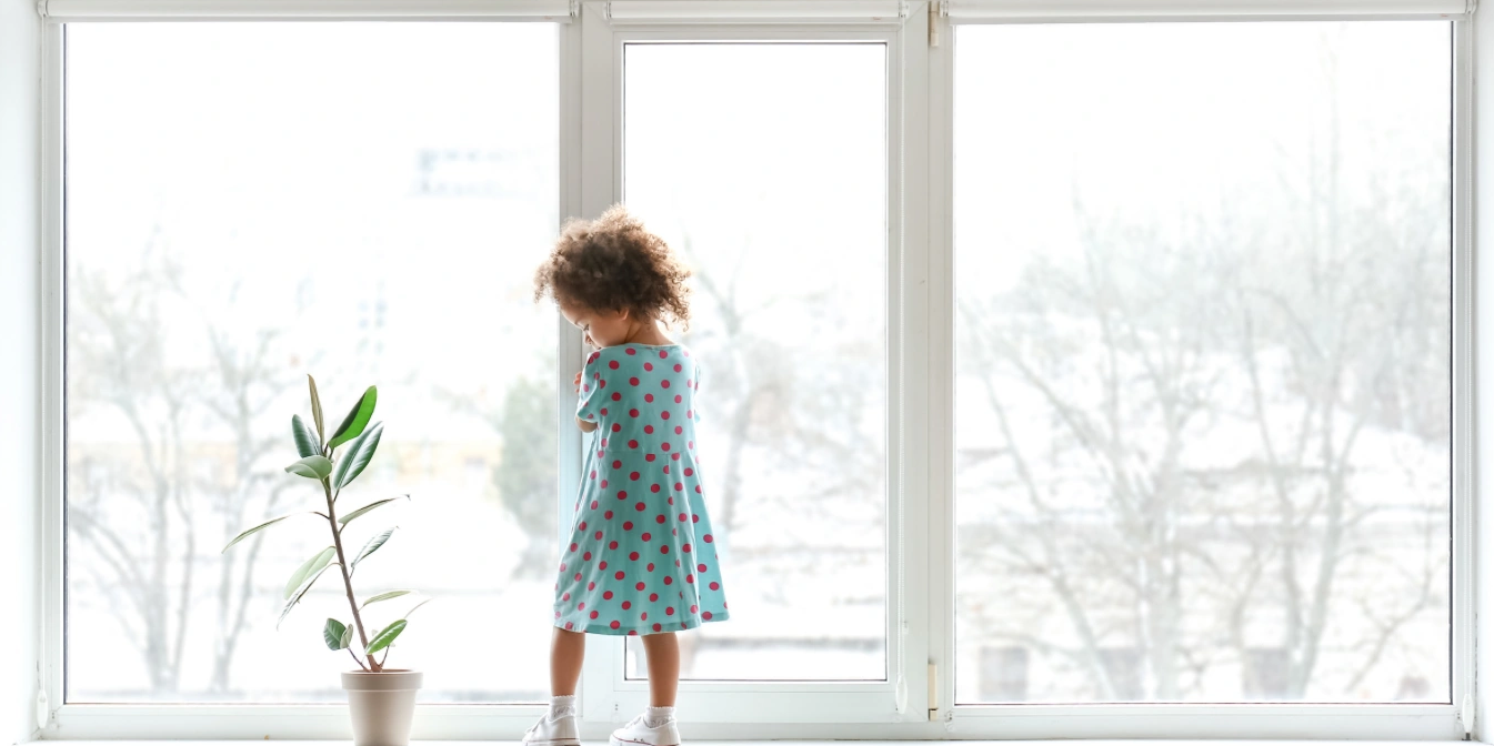 Toddler next to plant in clean home