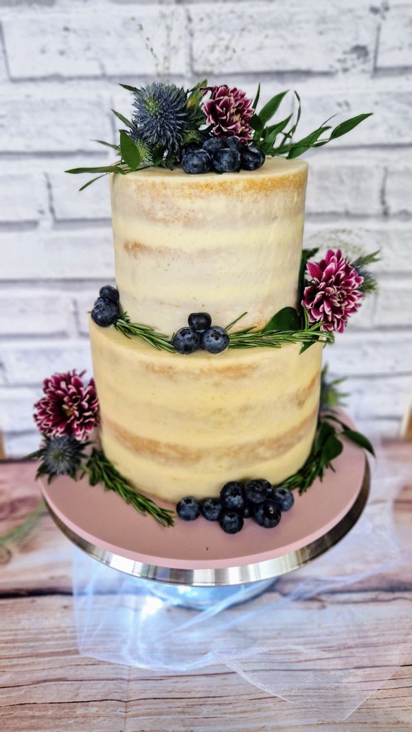 Rustic 2 tier semi-naked style wedding cake with flowers and berries