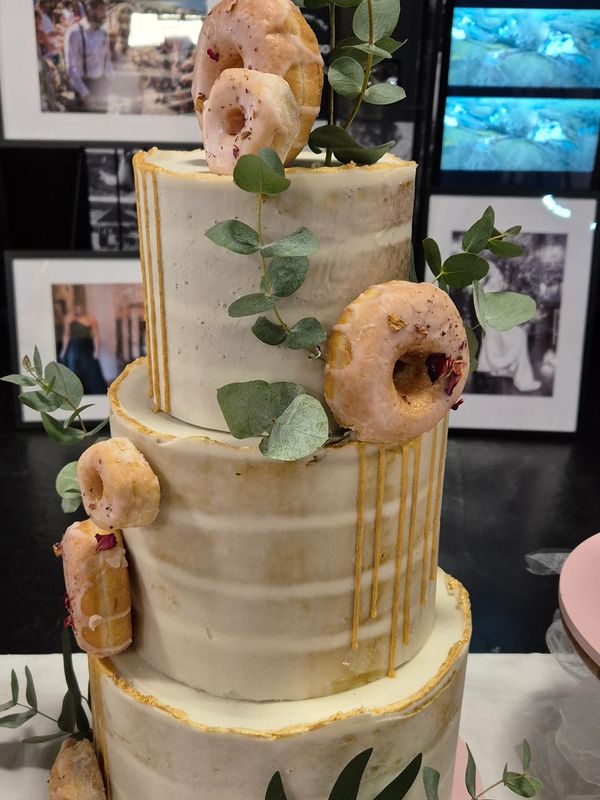 3-tier semi-naked style wedding cake with gold drip, donuts, and eucalyptus leaves