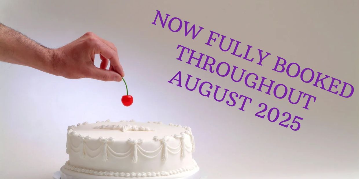 A hand adds finishing decoration of a cherry to a cake
