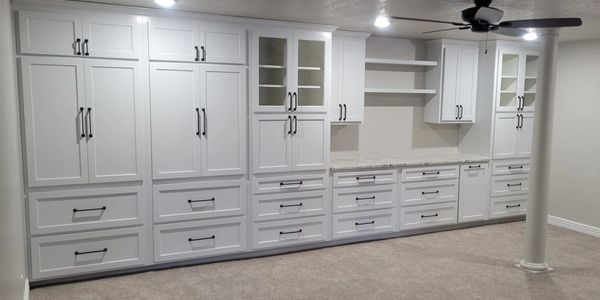 Long white built-in cabinets with black handles in a spacious room.