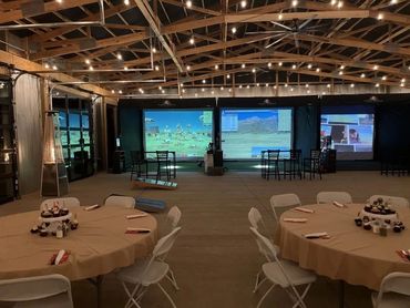 Event hall with timber trusses, string lights and set banquet tables