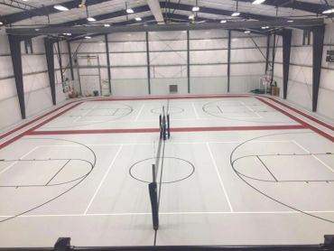 Indoor basketball and volleyball courts inside a large steel building
