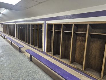 Wood locker stalls with purple benches along a long locker room