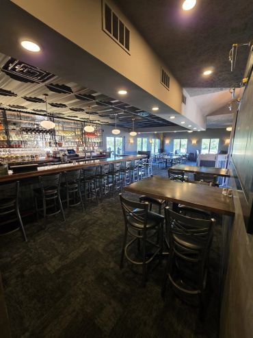 Restaurant dining room and bar with high-top tables and dark ceiling