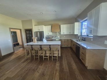 Open kitchen with a white-topped island, bar seating and hardwood floors