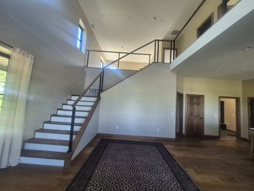 Open staircase with black metal railing leading to a loft overlook