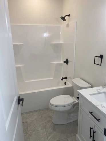 Condo bathroom with tub-shower, white vanity and black fixtures
