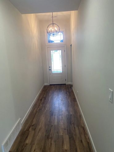 Long entry hall with wood-look flooring and a transom over the front door
