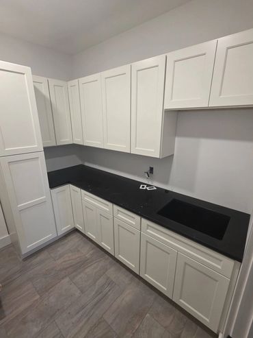 White shaker cabinets with black countertops and a deep sink