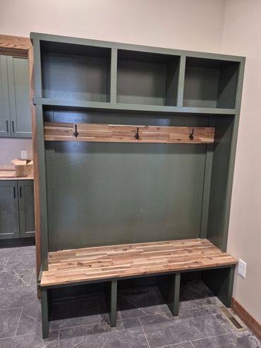 Green mudroom locker built-in with a butcher-block bench and coat hooks