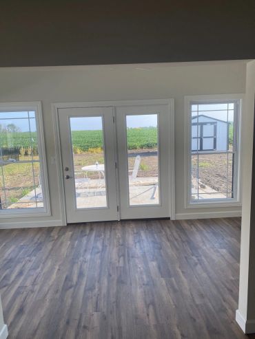 French patio doors flanked by windows over new plank flooring
