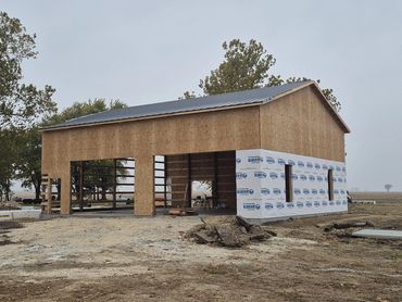 Post-frame building with roof steel on and walls being enclosed