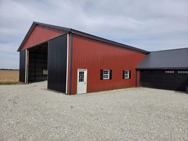 Red and black post-frame building with an open drive-through bay