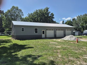 Long gray garage building with three white overhead doors