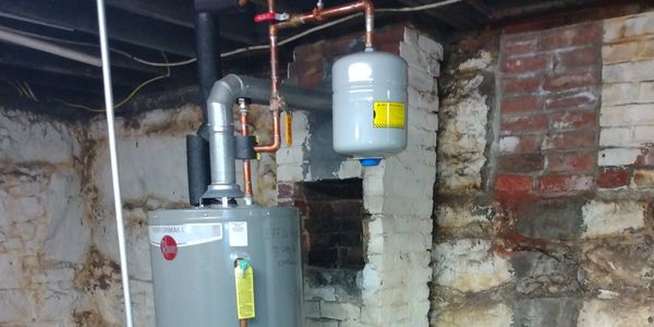 New water heater installed in a basement with exposed brick walls.