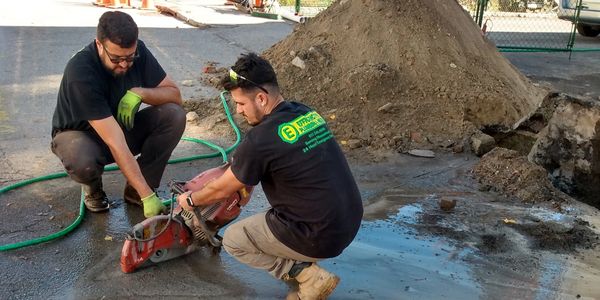 Two men using a concrete saw on a construction site.