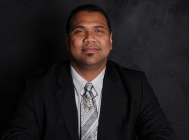 Antwain Thomas is shown smiling in a dark suit with a silver tie.