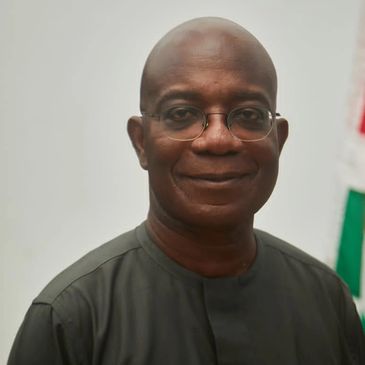 Mr. Kojo Mattah is shown with his glasses on and wearing a green shirt while smiling.