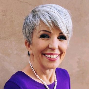 Doctor Pauline Crawford is shown with gray hair, a purple dress, and pearls around her neck.