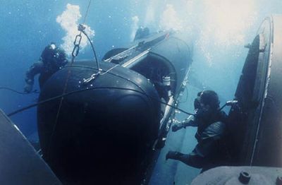 Navy SEALS are shown entering a smaller mobile submarine.