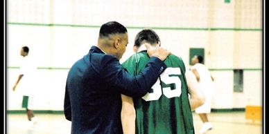 Coach offering guidance to a basketball player during practice at Keith Coleman Academy.