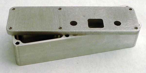 A small, metal, machined box and lid assembly that is zinc coated. 