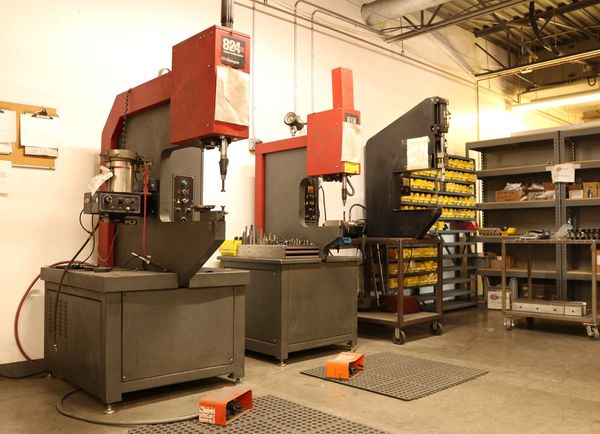 Three hardware presses in a warehouse ready for assembly. 