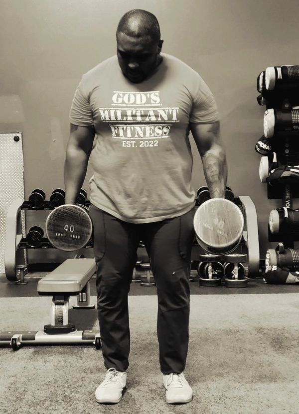 Man lifting 40-pound dumbbells in a gym wearing a fitness t-shirt.