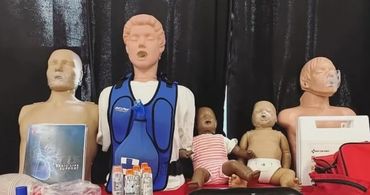 CPR training mannequins and medical supplies displayed on a table.