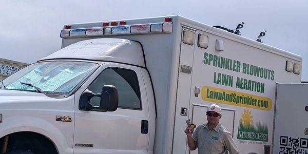 Nature’s Carpet Lawn & Sprinkler technician beside a branded service truck in the Denver metro area
