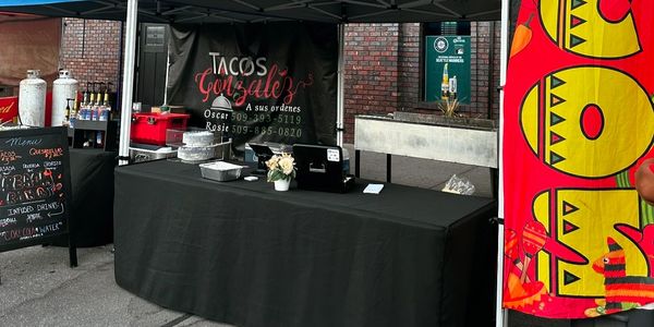 Tacos Gonzalez catering setup with blue tents and taco banner.