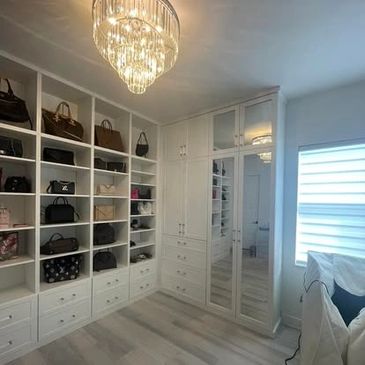 A well-organized walk-in closet with handbags and a chandelier.