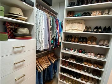 Organized closet with clothes, shoes, and hats.