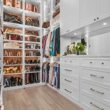 Bright, organized walk-in closet with shoes, handbags, and clothes.
