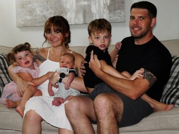 Family of five sitting on couch smiling.