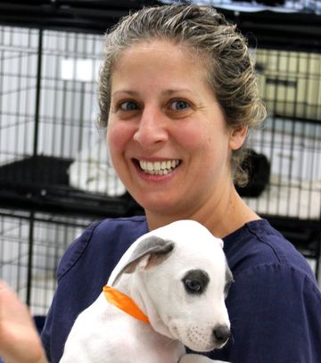 Woman with blonde hair smiling and holding puppy