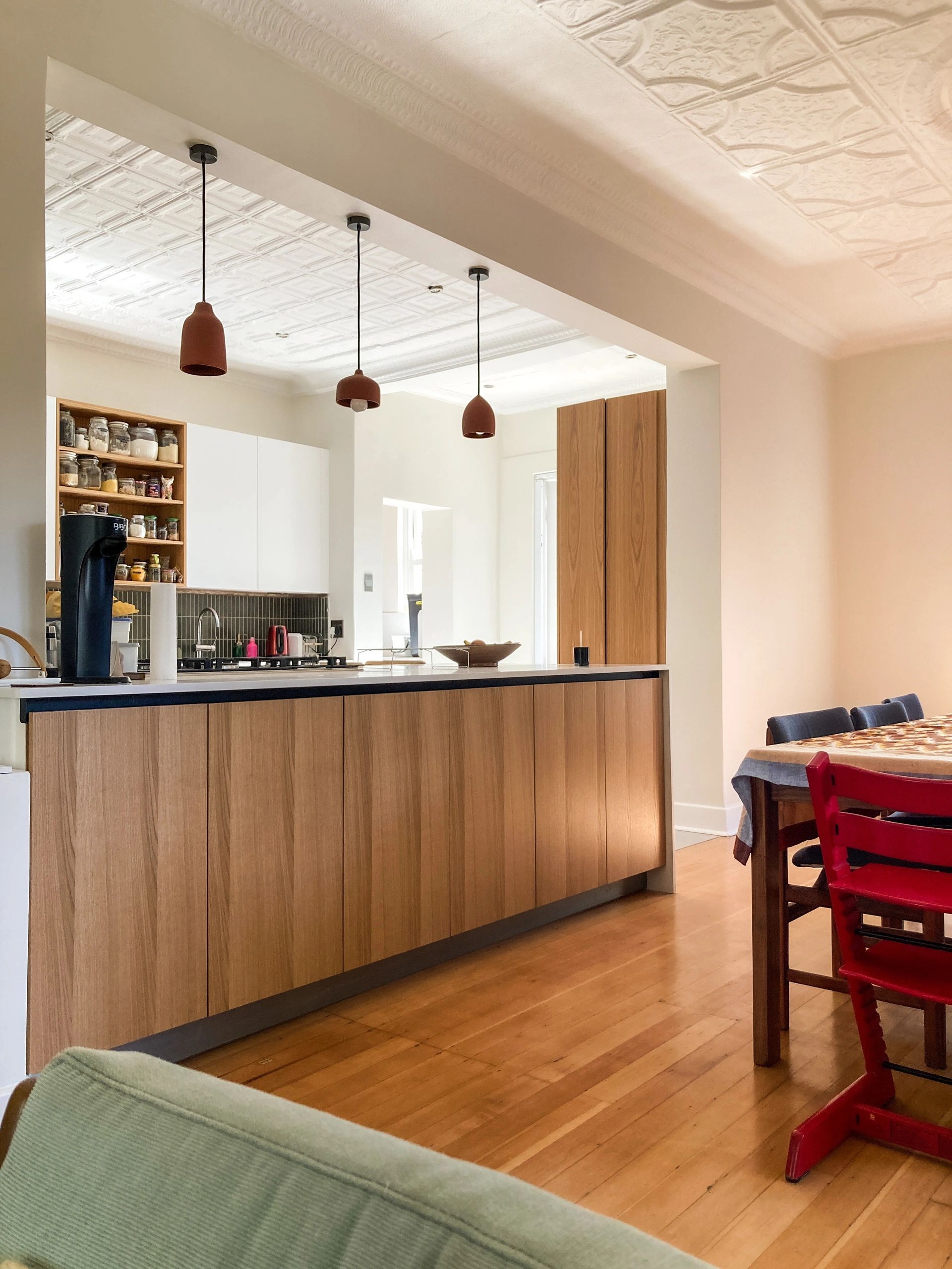 Open-plan-living-room-with-wooden-floors-featuring-oak-and-white-kitchen-with-clay-light-fittings