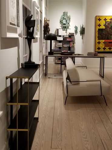 Modern art gallery with sculptures, paintings, and books in a minimalist space.