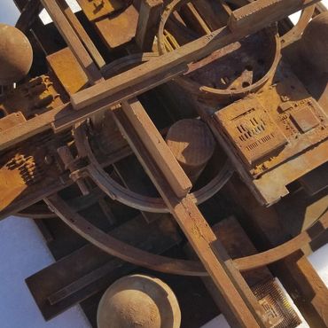 Rusty metal sculpture with geometric shapes on a snowy surface.