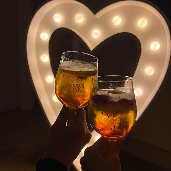 Two glasses of Aperol Spritz with a lit heart-shaped background.