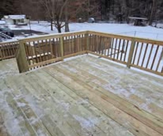 Snow-dusted wooden deck on a cold winter day.