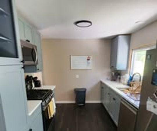 Modern kitchen with stainless steel appliances and dark wood flooring.