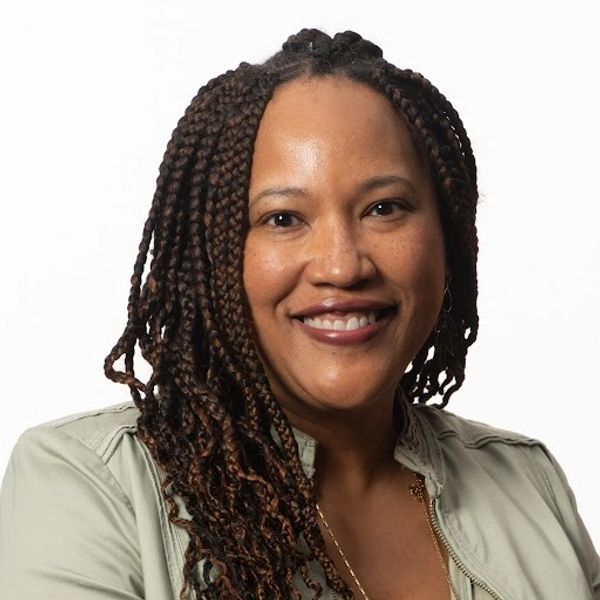 Smiling woman with braided hair wearing a light green jacket.
