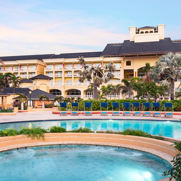 Luxury resort with pool and palm trees under a clear sky.