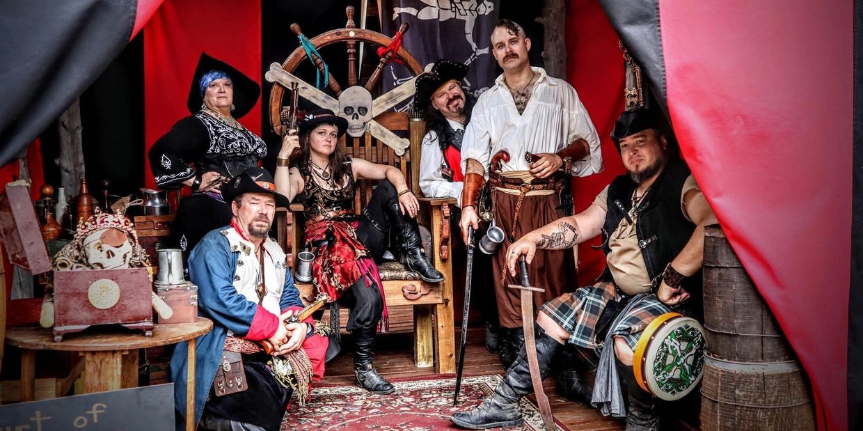 Group of people dressed as pirates posing in a decorated room.