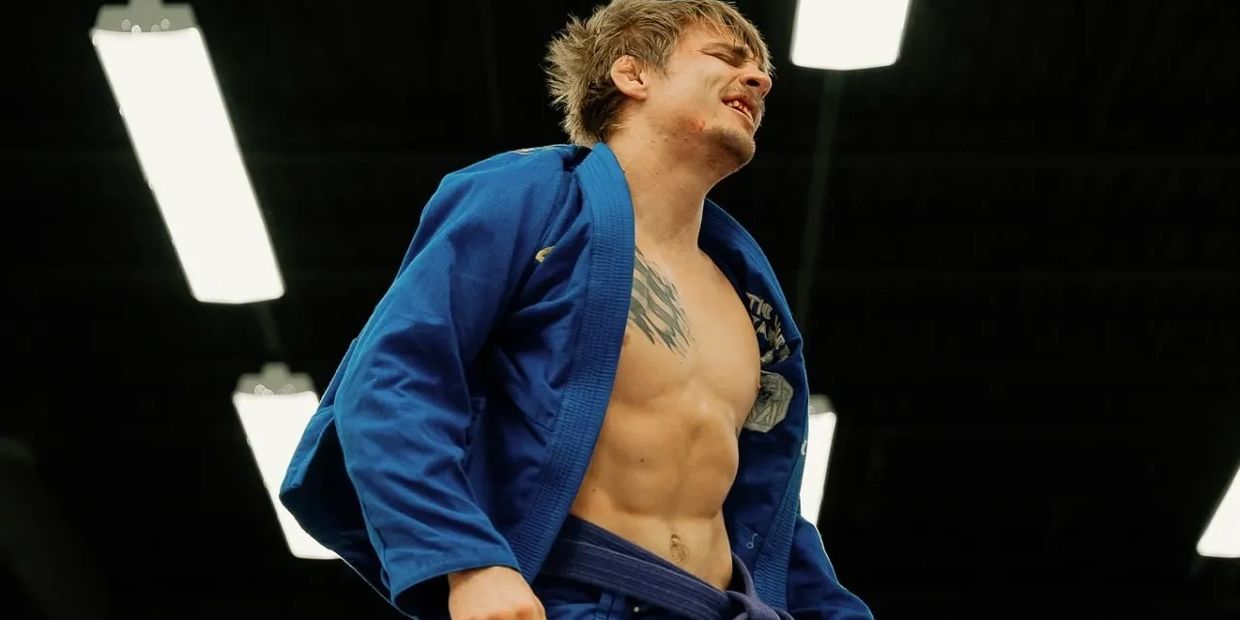 Man in a blue martial arts gi showing pain or exertion.
