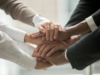 Various people putting their hands stacked together promising help and support